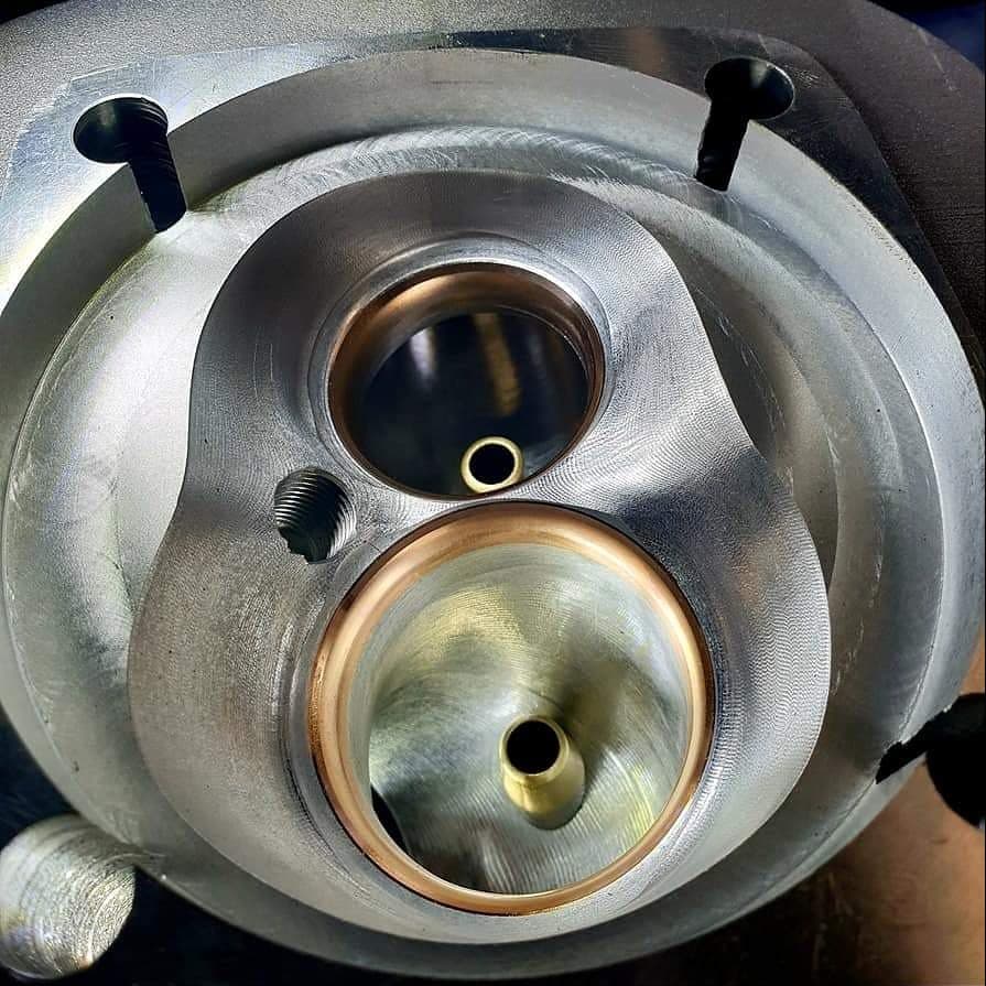 CNC-machined combustion chamber with intake and exhaust valve seats, close-up
