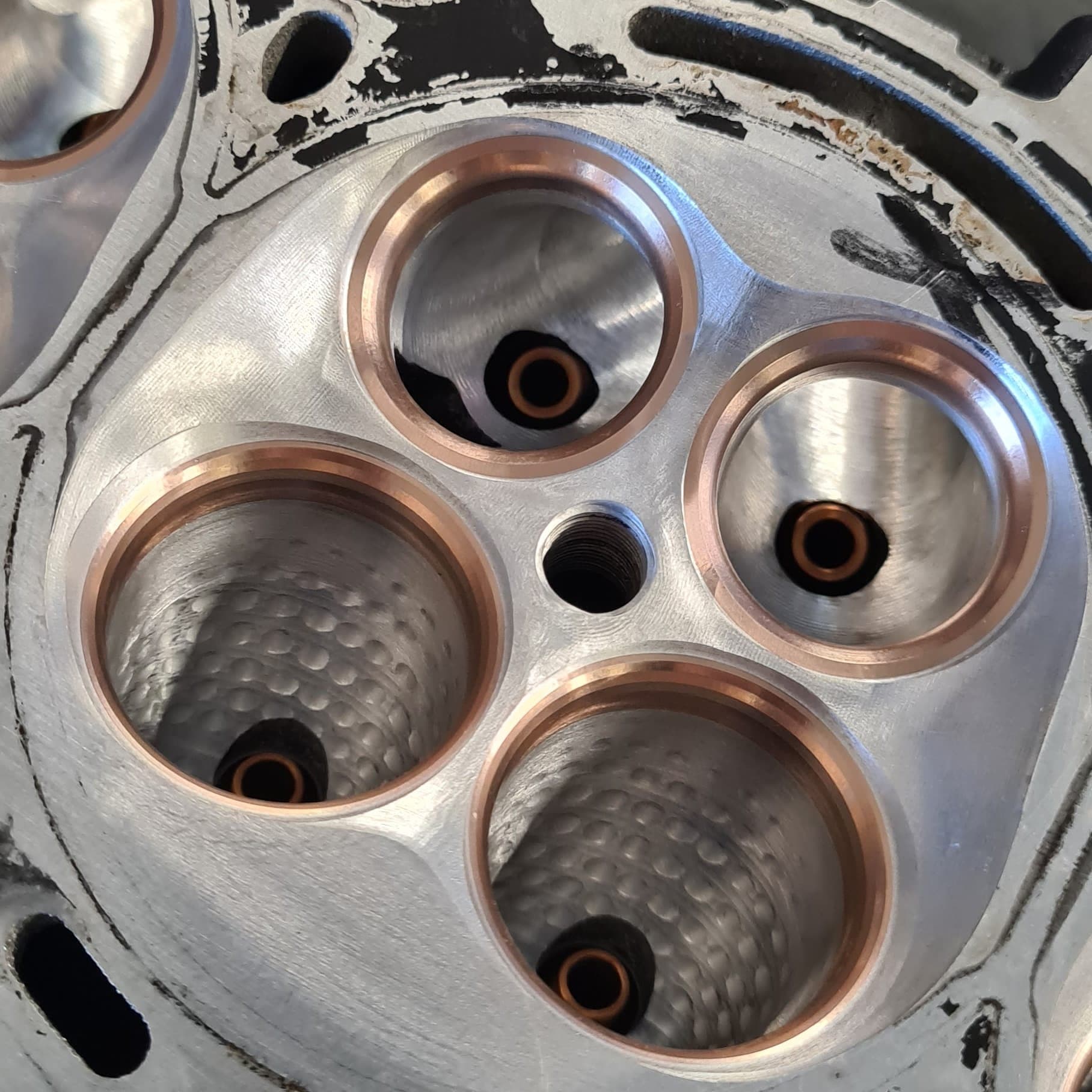 Close-up of three freshly CNC-machined port openings with bronze valve seat rings