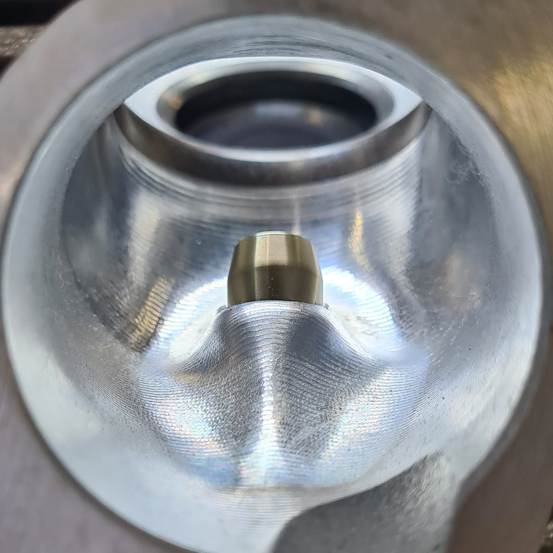 View into a freshly CNC-machined port with visible machining marks and valve seat ring