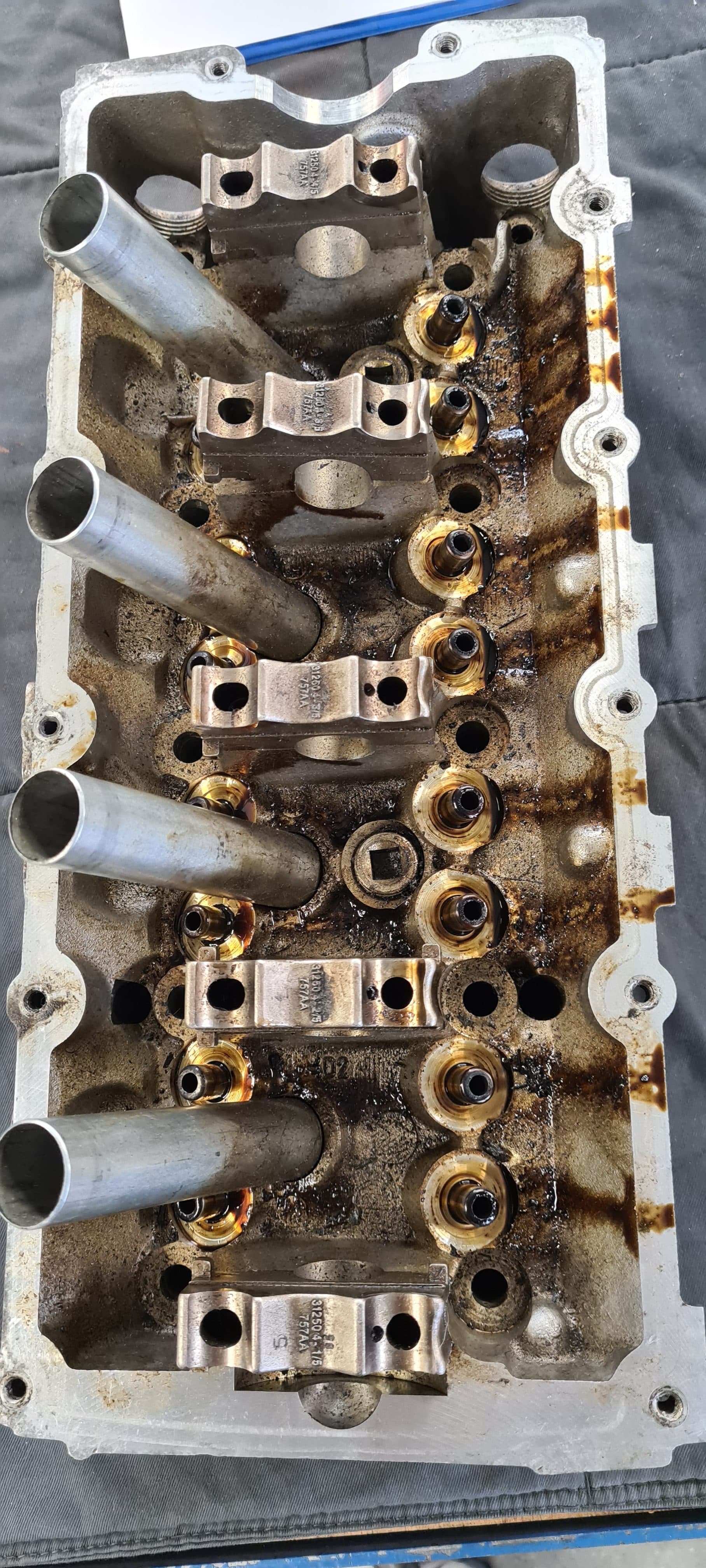 Heavily oil-stained valve cover before cleaning in the wash cabinet