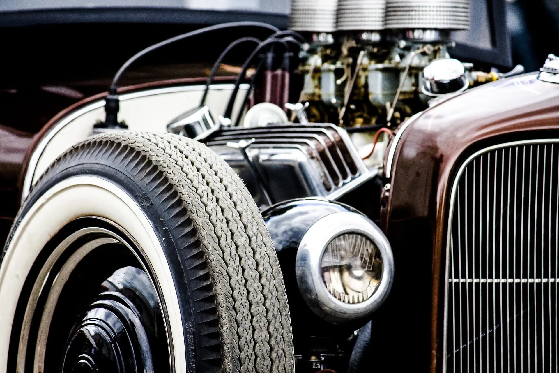 Open engine bay of a hot rod with three carburettors and whitewall tyres