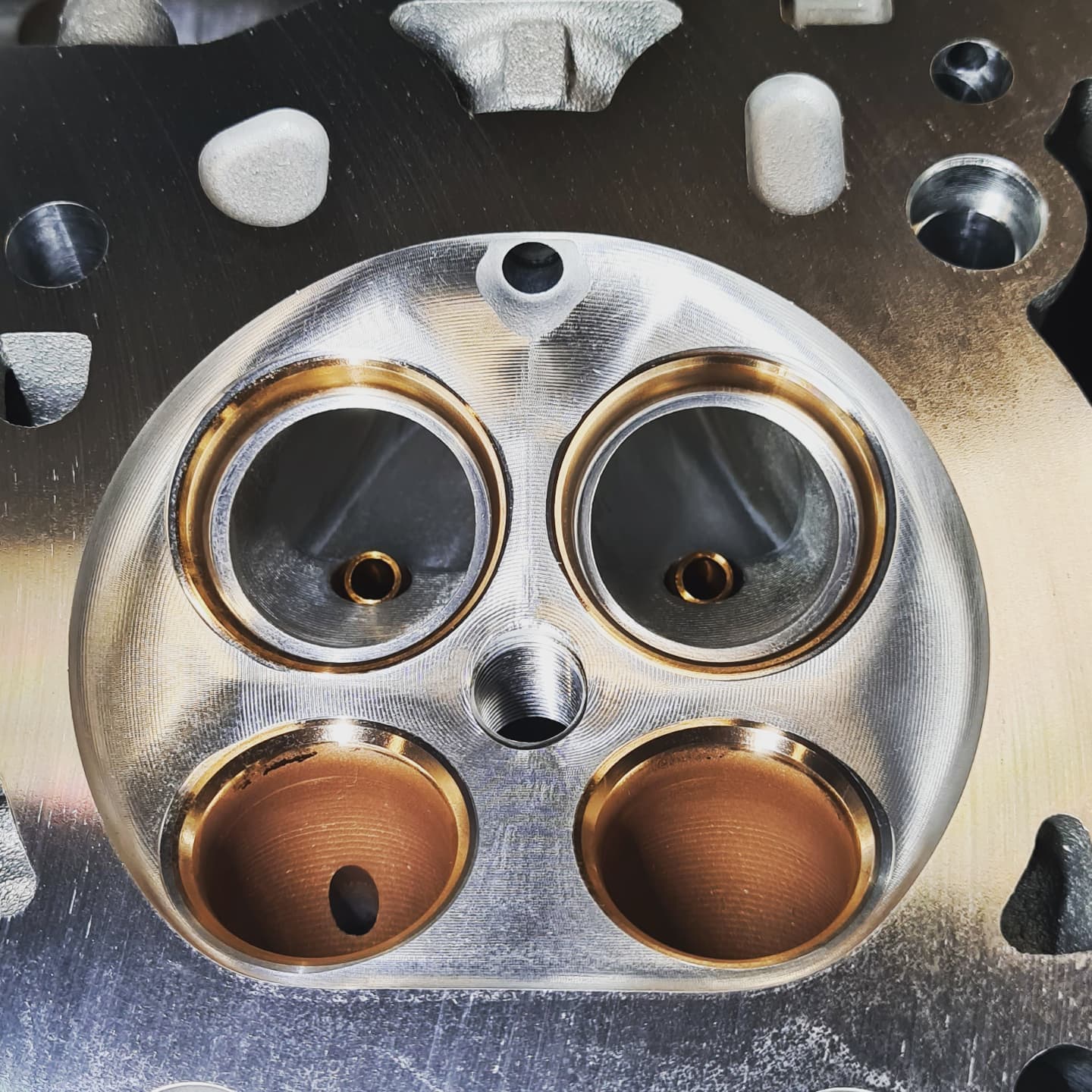 Close-up of CNC-machined combustion chambers and valve seats on a cylinder head